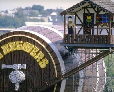 A figure of Bernie Brewer standing on the balcony of a small Bavarian-style chalet, next to a giant wooden beer barrel with BREWERS in gold letters.